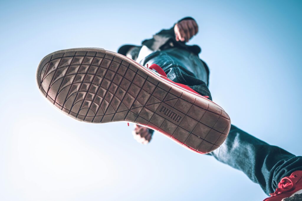 Low angle view of person wearing sneakers with focus on the sole against blue sky.